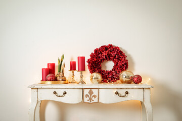 Weihnachtliche Dekoration mit roten Kerzen auf einem weißen Sideboard