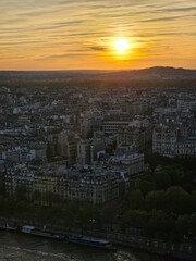 Paris, France - April 12, 2024: Aerial view to the city of Paris, during the golden hour between modern skyscrapers and old buildings. Beautiful sunset over the city reflected on the buildings.