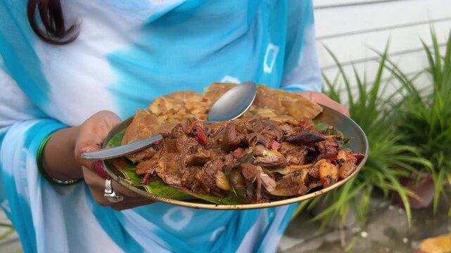 A girl holding a plate of Sukha mutton and paratha made with coconut oil. No face video