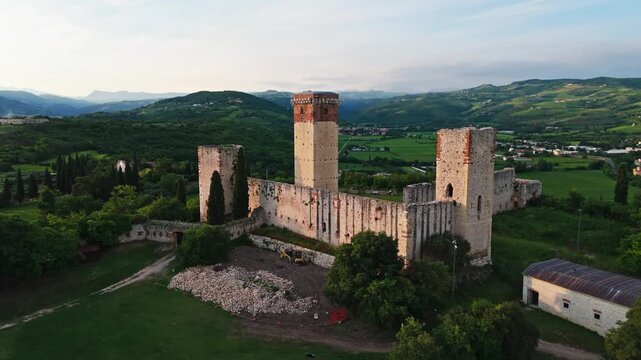 Montorio Veronese Castle, Verona. Aerial shot of the large medieval castle at sunset. Walls and tall tower loom over the countryside. 4k, 50 fps.