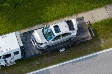 Traffic accident with tow truck hauling smashed vehicle on car crash site. First responders helping...