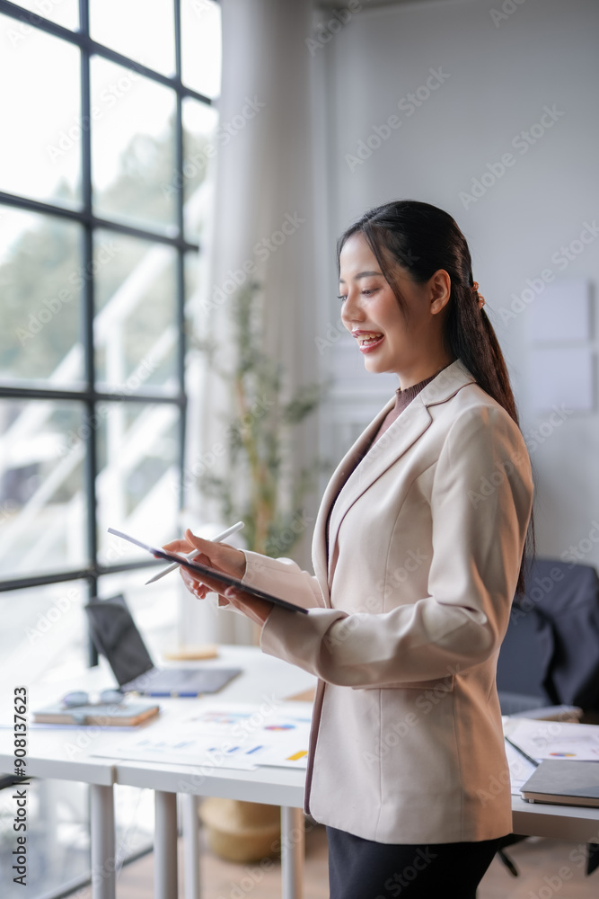 Poster young manager smiling and working on a digital tablet with a stylus in a modern office