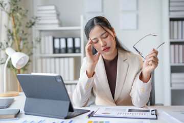 Young manager having a headache while analyzing financial charts at her desk in a modern office