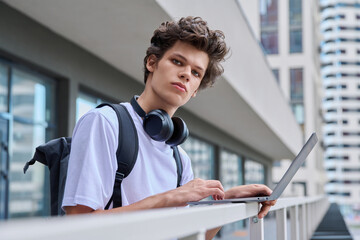Obraz premium Young handsome male using laptop computer, modern city skyscrapers background