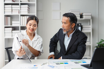 Businesswoman pointing at documents on clipboard while having a meeting with a senior businessman in the office