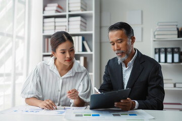 Senior manager and a young associate are working together on a financial report in the office