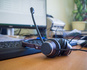 headset on the background of the keyboard and monitor in the office window. a concept for...