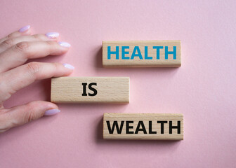 Health is Wealth symbol. Concept word Health is Wealth on wooden blocks. Doctor hand. Beautiful pink background. Medicine and Health is Wealth concept. Copy space