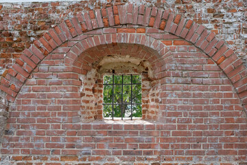 Fragment of an ancient brick fortress, window with metal bars, view from inside