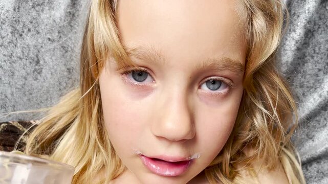 An eight-year-old girl drinks milk from a glass. Close-up view of a child drinking milk from a glass. High quality 4k footage