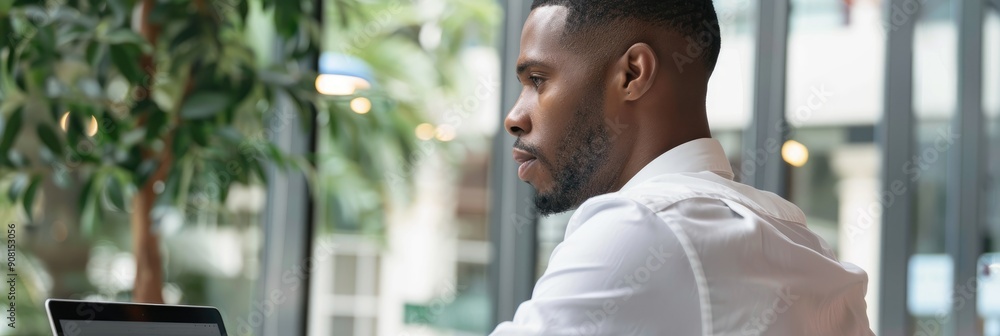 Poster black businessman working on laptop computer in side view focusing on task