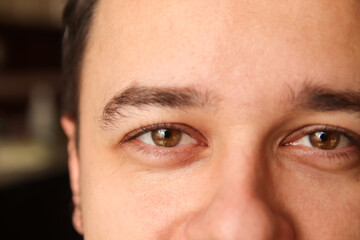 Close-up of a young brunette man with brown eyes, intense gaze. Young man with deep brown eyes.
