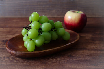 木製の皿にのせたマスカットと林檎