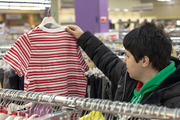 A young woman chooses casual clothes in a supermarket. Retail trade. Consumer activity.