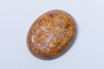 Close up studio photo of an oval jaspar palm stone on white background