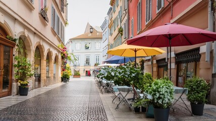 Fototapeta premium Charming Outdoor Cafe Seating in Historic Euromy City Amidst Colorful Umbrellas and Quaint Architecture