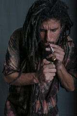 restaman lighting up a cigarette hippie style clothing studio shot dark mood smoking habits 