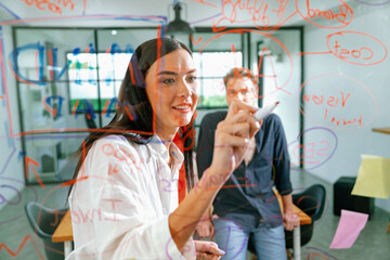 Professional business team brainstorming and working together about marketing project. Female caucasian leader writing idea on stick note while coworker present her idea confidently. Immaculate.