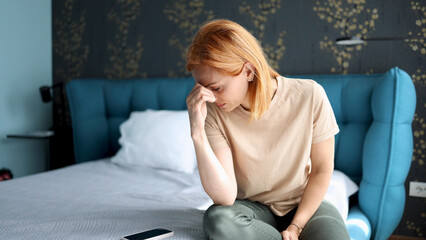 Woman sitting on her bed at home, feeling depressed and lost
