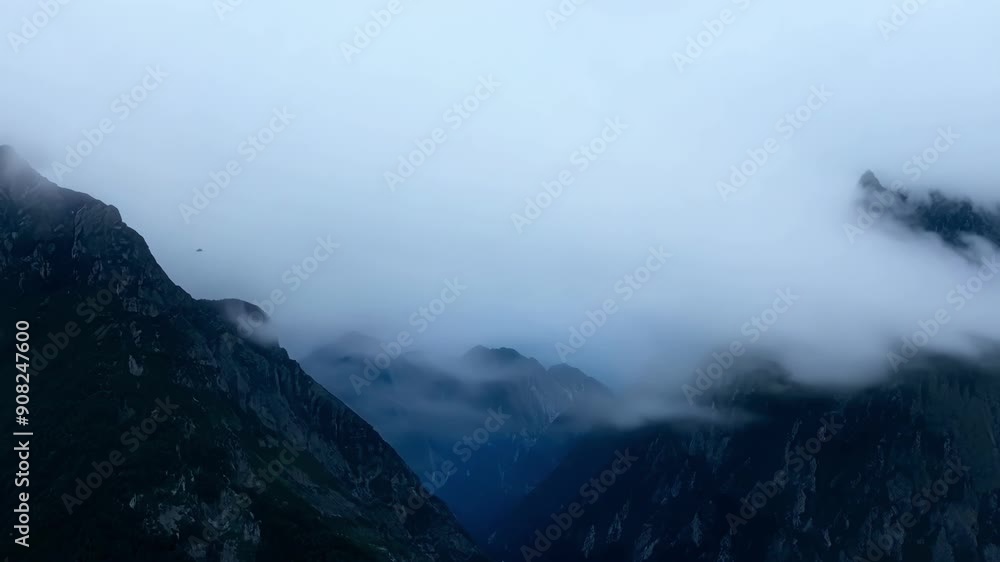 Poster the mountain peaks clothed in layers of fog and clouds seem to blend into the sky creating an eerie 
