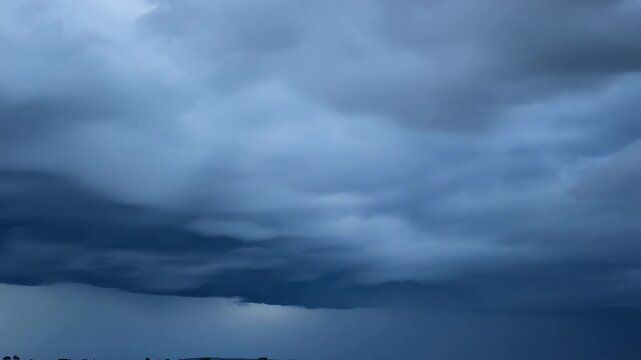 The rolling storm clouds move with alarming speed appearing to devour the blue sky in their path.