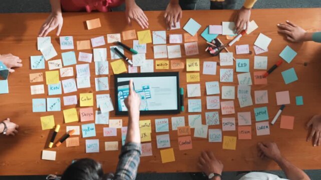 Aerial view of developer team discussing and showing digital program and writing by using Ux Ui design. Top down view of business people develop wireframe prototype for phone and computer. Symposium.