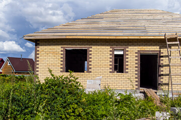 Unfinished country brick house. Wooden beams and roof rafters. House without windows and doors