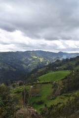Fototapeta premium hermoso paisaje de montaña con pueblo, campos verdes, nubes, pasto, arboles, naturaleza,