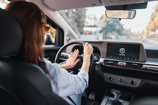 A woman in the driver's seat of a car, one hand on the steering wheel, looking forward, capturing the essence of driving and travel while highlighting the focus and responsibility of operating a