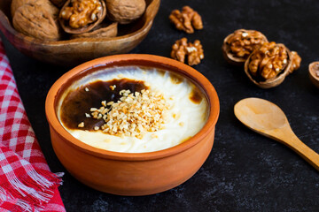 Baked rice pudding made with walnut milk, with walnuts in a casserole bowl, on a black surface.Vegan food