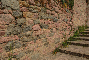stone wall, texture, Medieval natural stone wall, pink granite, French masonry stone wall, background for photo.,moss, plants on the stone wall