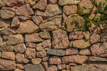 stone wall, texture, Medieval natural stone wall, pink granite, French masonry stone wall, background for photo.,moss, plants on the stone wall
