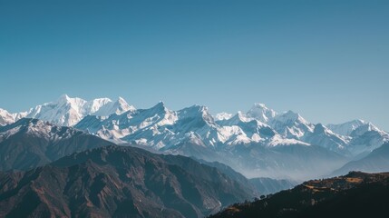 The majestic himalayan mountain range is bathed in sunshine, with its snow-capped peaks piercing the clear blue sky