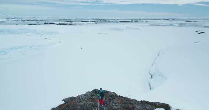 Tourist man skiing Antarctic snow mountain slope nature landscape. Alpine tourism in wild harsh conditions. Winter trekking extreme sport. Antarctica people travel and exploration. Aerial drone shot