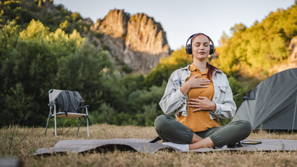 Young woman with headphones have guided meditation on the mountain