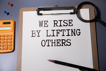 We rise by lifting others wisdom quote - handwriting on a napkin with fresh grapes