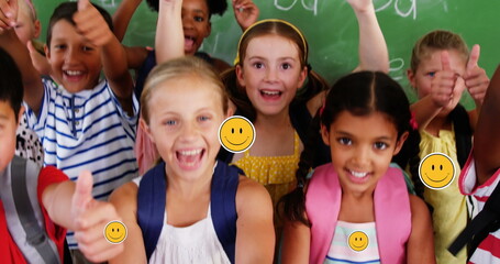 Image of falling icons over diverse school children with thumbs up in class at school