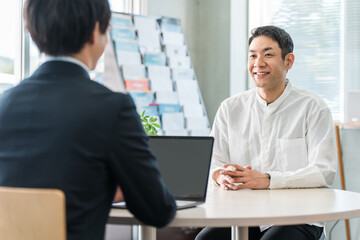 自動車保険の相談に来た中年男性と接客対応する男性ビジネスマン
