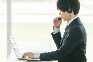 ヘッドセットをつけてオンライン会議をする若いビジネスマン
