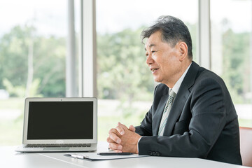 接客・カウンセリング・面談するスーツ姿のアジア人シニア男性ビジネスマン
