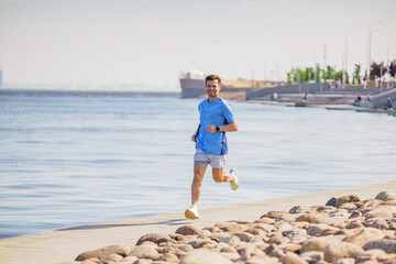 A man in a blue athletic outfit running along a waterfront path on a sunny day, exuding energy and health.