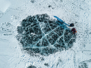 Aerial view of tourist while looking to iced cracks surface on the frozen lake of Baikal lake,...