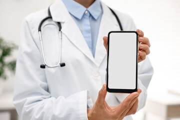 Doctor showing smartphone with blank screen in hospital, selective focus