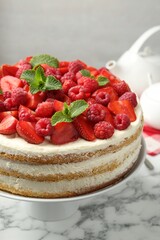 Tasty sponge cake with fresh berries and mint on white marble table, closeup