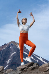 Woman happy and engaged in yoga, is standing in pose with her arms raised against background of...