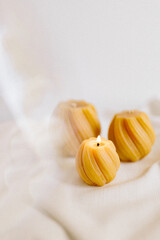 Handmade candles from natural beeswax in the shape of flowers, bears on a white background. Hobby. Handmade present. Gift. Artistic photo of beekeeping products in white room. Mockup. 