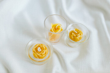 Handmade candles from natural beeswax in the shape of flowers, bears on a white background. Hobby. Handmade present. Gift. Artistic photo of beekeeping products in white room. Mockup. 