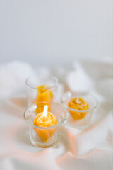 Handmade candles from natural beeswax in the shape of flowers, bears on a white background. Hobby. Handmade present. Gift. Artistic photo of beekeeping products in white room. Mockup. 