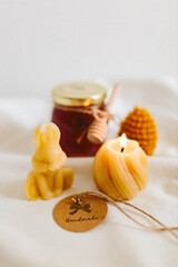 Organic honey in a glass jar and burning candles made of natural handmade wax on a white background. Beekeeping products. Small business. Farm.