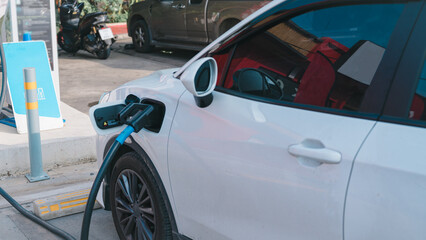 Fototapeta premium Sustainability concepts. Electric vehicles. A white car is being charged at a charging station.